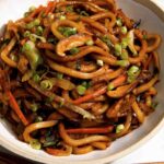 Udon noodles in a bowl with green onions on top.