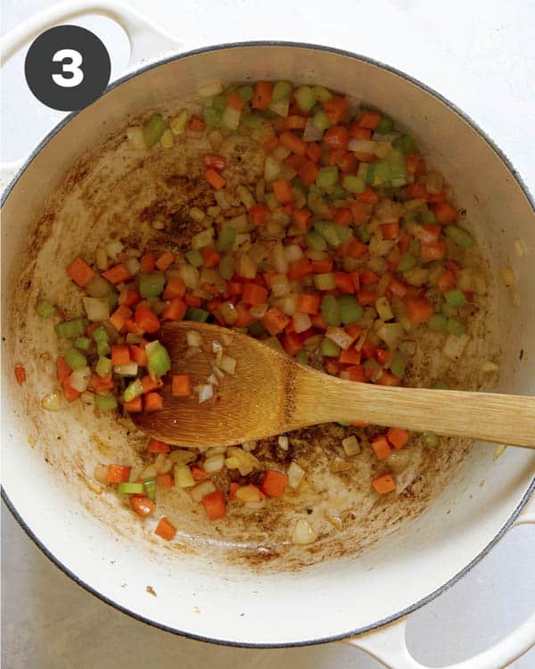 Celery, carrot, garlic and onion cooking in a pot to make soup. 