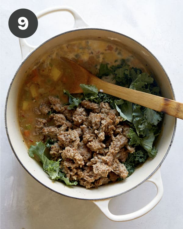 Adding in sausage, kale, and milk to make a soup recipe.