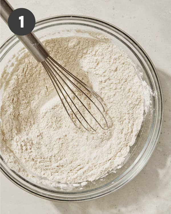 Dry ingredients whisked together in a glass bowl for baked pumpkin donuts.
