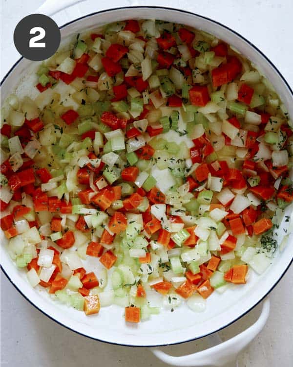 Vegetables and herbs in a pot for chicken and dumplings.