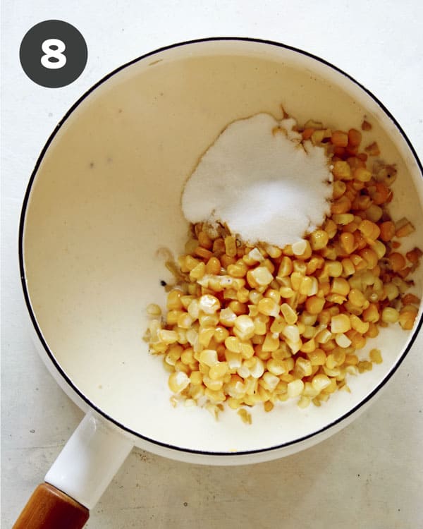 Corn added into a skillet with cream to make creamed corn.