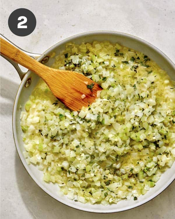 Onions and celery with herbs in a skillet. 