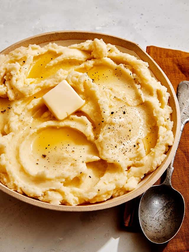 Easy mashed potatoes recipe in a bowl with melted butter.