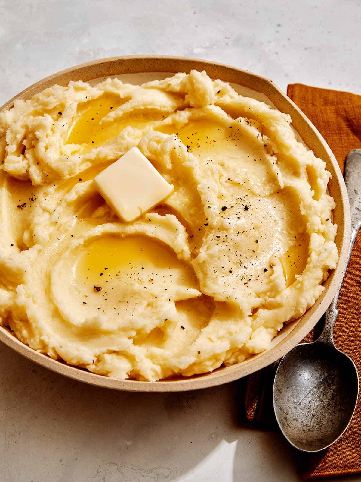 Mashed potatoes in a bowl with a spoon on the side.
