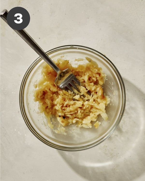 Roasted garlic mashed in a bowl with a fork. 