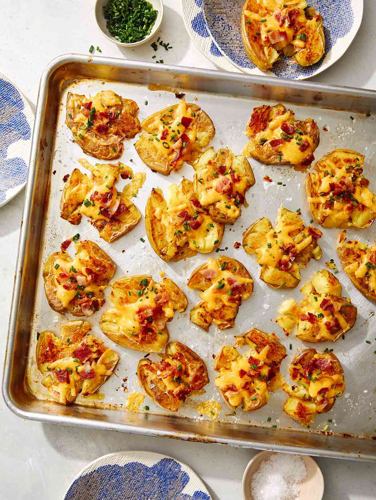 Smashed potatoes recipe on a platter with chives on the side.