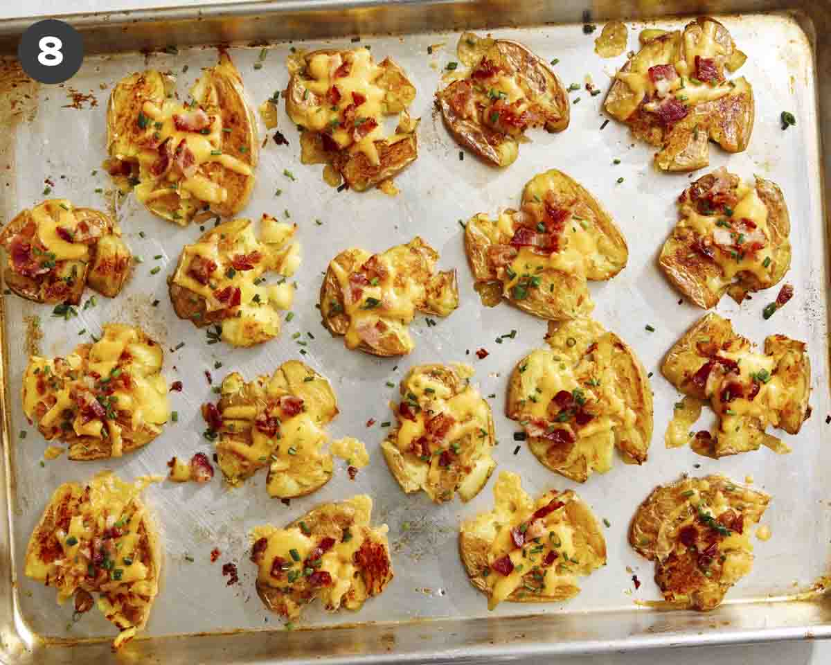 Smashed potatoes on a baking sheet topped with chives. 