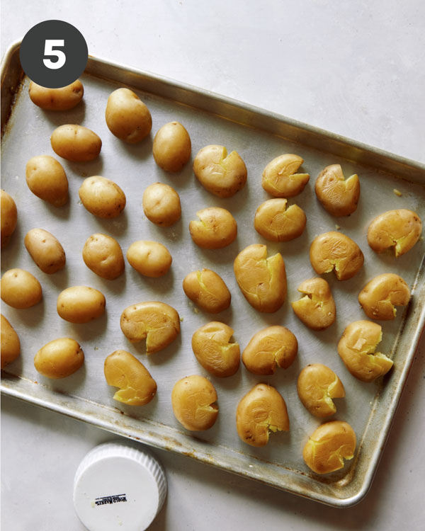 Potatoes gently smashed on a baking sheet. 