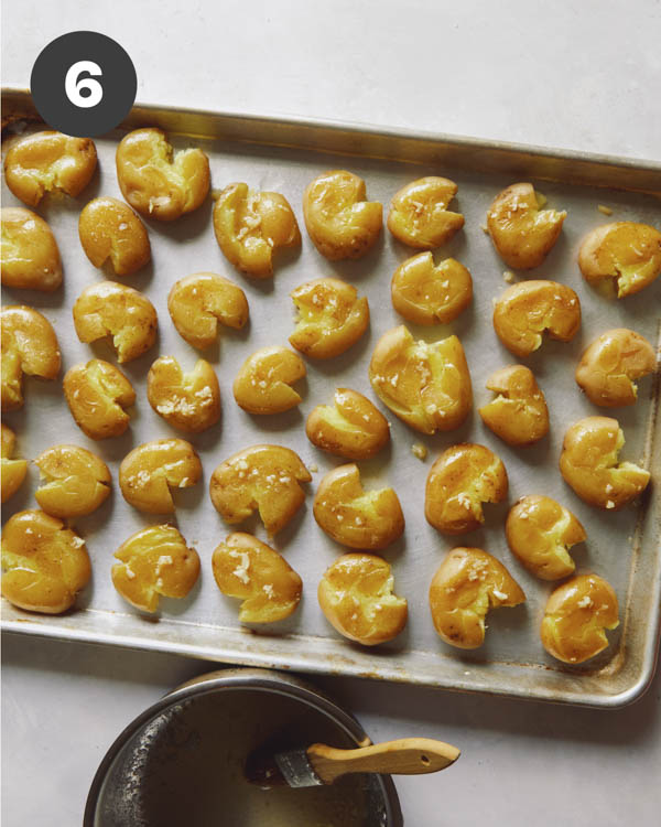 Smashed potatoes being brushed with garlic butter. 