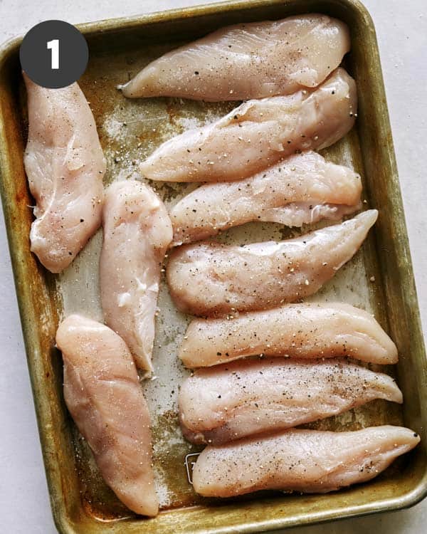 Chicken tenders being seasoned.