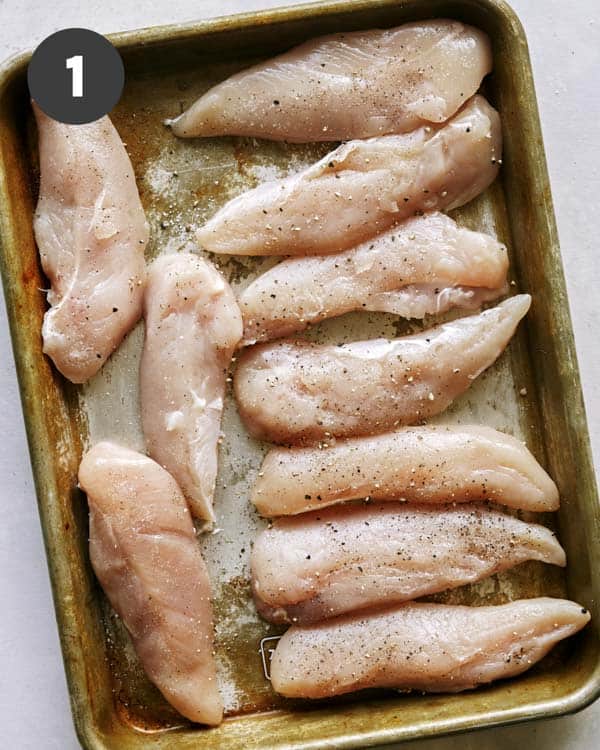 Chicken tenders being seasoned. 