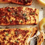 Air fryer salmon on a platter with lemons on the side.