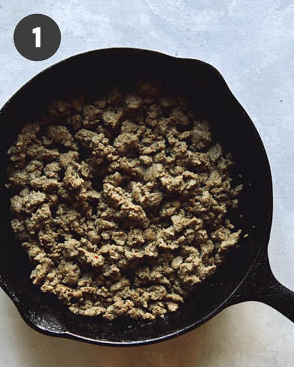 A cast iron skillet with breakfast sausage browned in it for a breakfast casserole recipe.