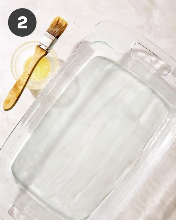 Buttering a baking dish for parmesan potatoes.