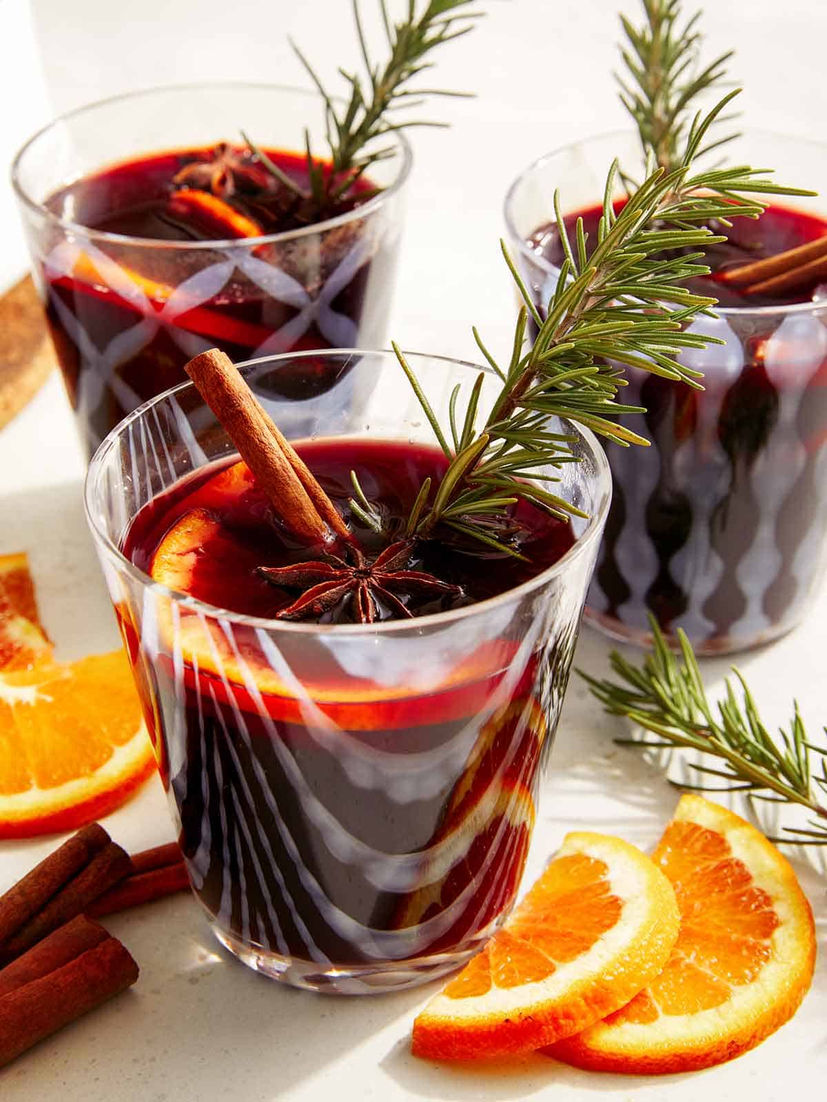 Mulled wine in glasses with garnish around them. 