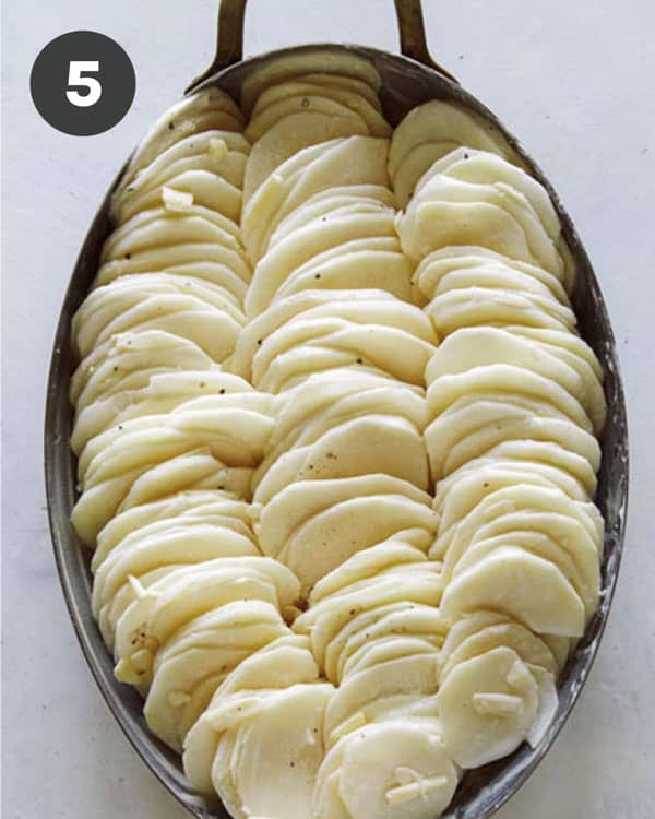 Thinly sliced potatoes in casserole dish to make potatoes gratin.
