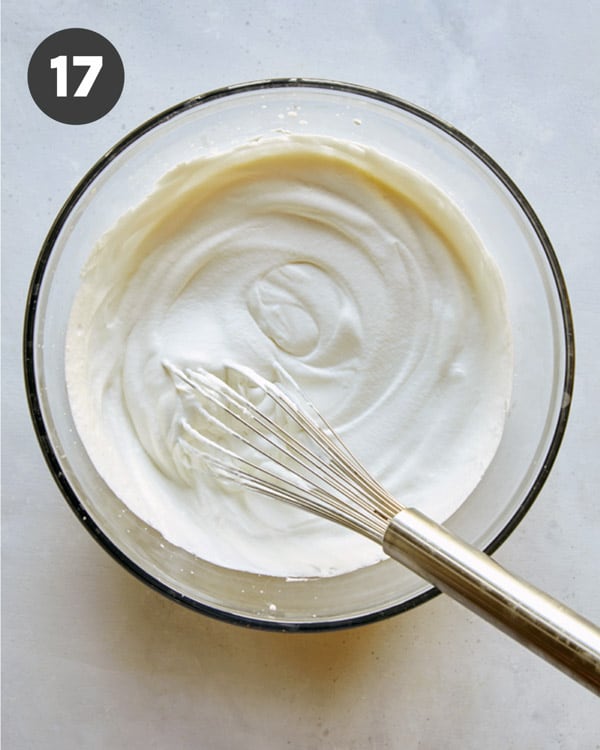 Whipped cream in a glass bowl with a whisk for sticky toffee pudding.