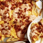 Animal style fries on a baking sheet with dressing on the side.