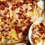 Animal style fries on a baking sheet with dressing on the side.