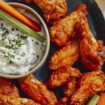 Air fryer buffalo wings on a platter with beer on the side.