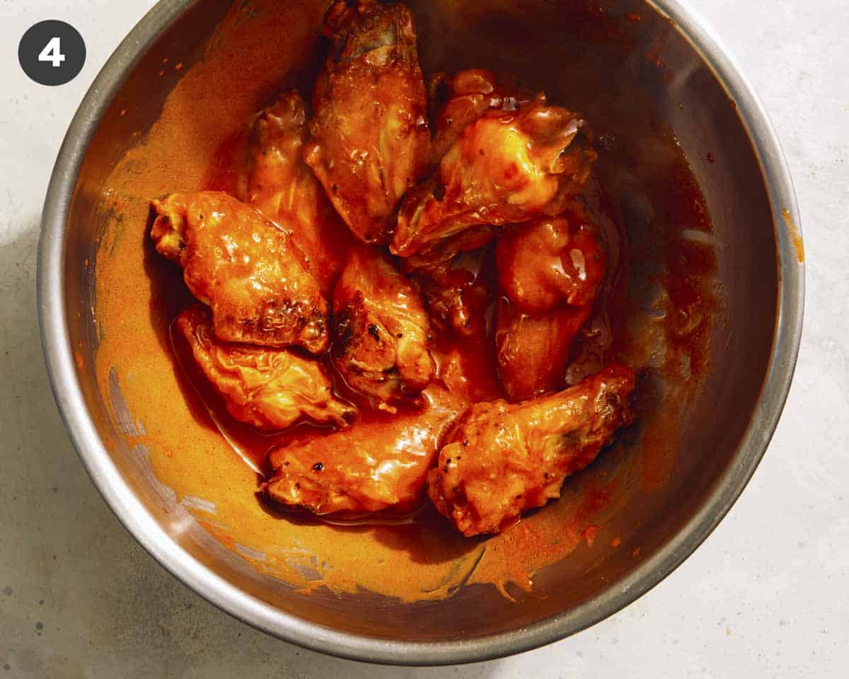 Buffalo wings in a bowl tossed with buffalo sauce.