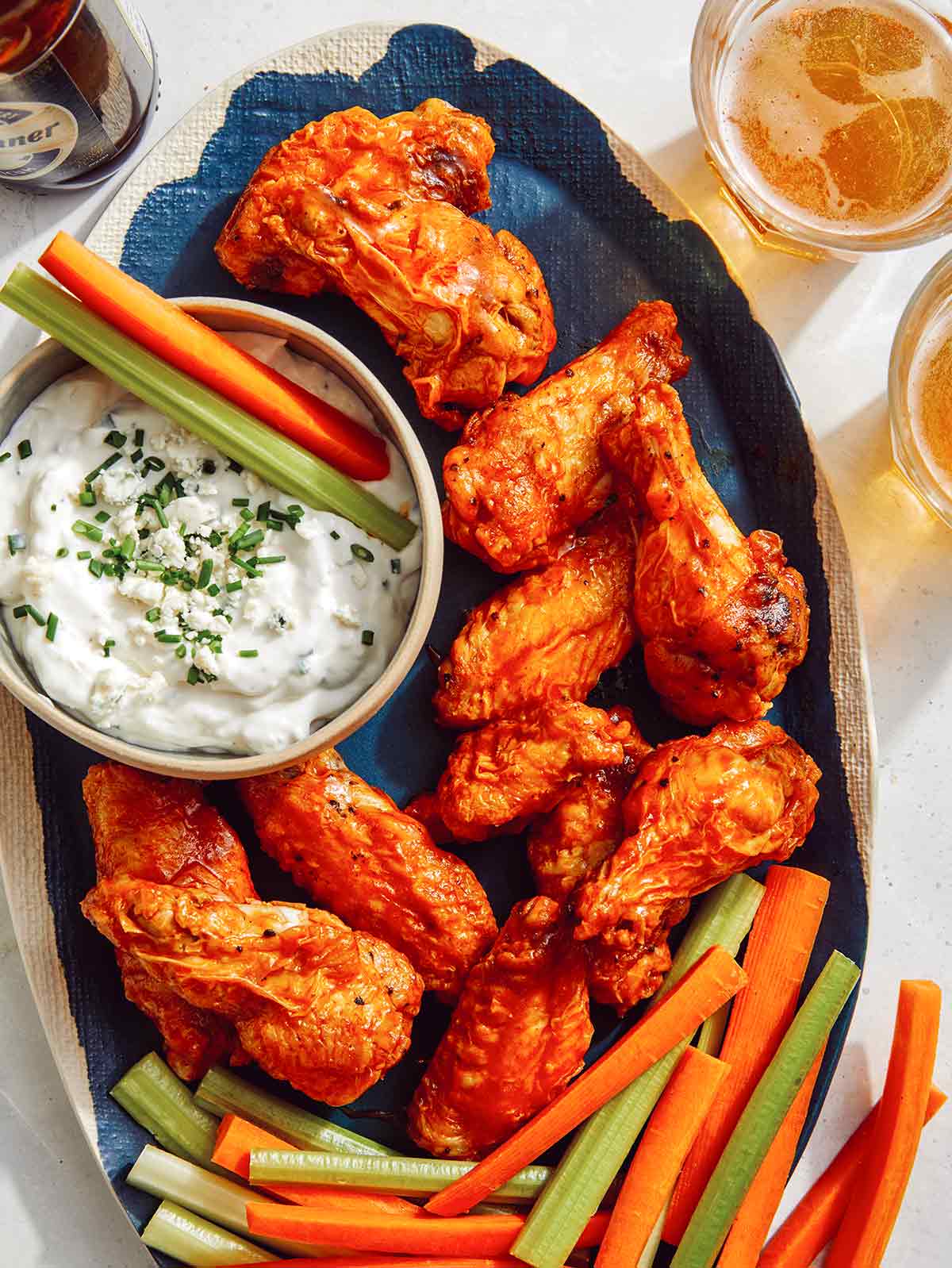Air fryer buffalo wings on a platter with beer on the side.