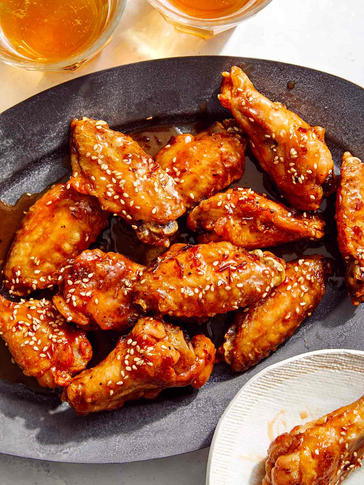 Air fryer chicken wings on a platter with beer next to it. 