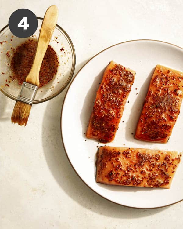 Salmon being brushed with a honey mustard. 