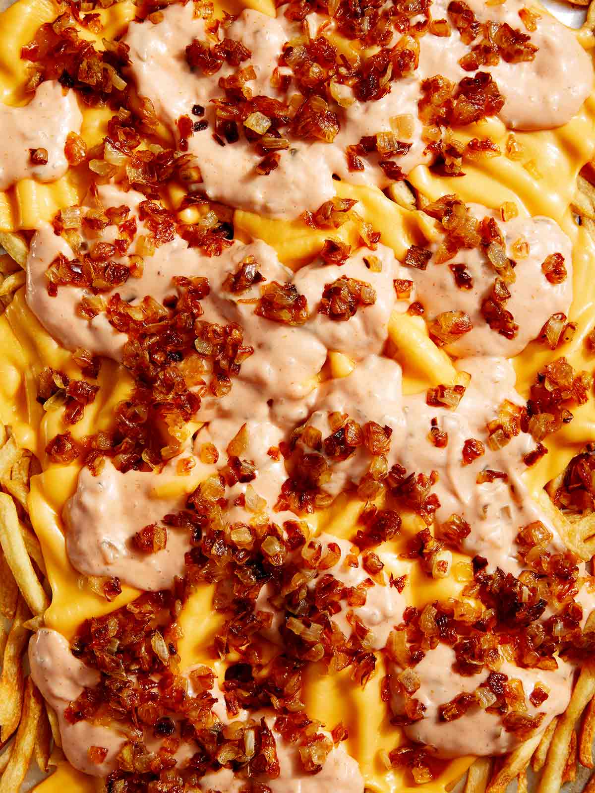 Animal style fries on a baking sheet up close.