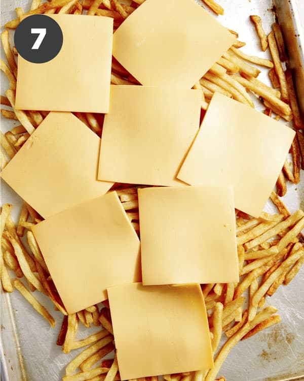 Fries with cheese slices on top ready to be baked in the oven.
