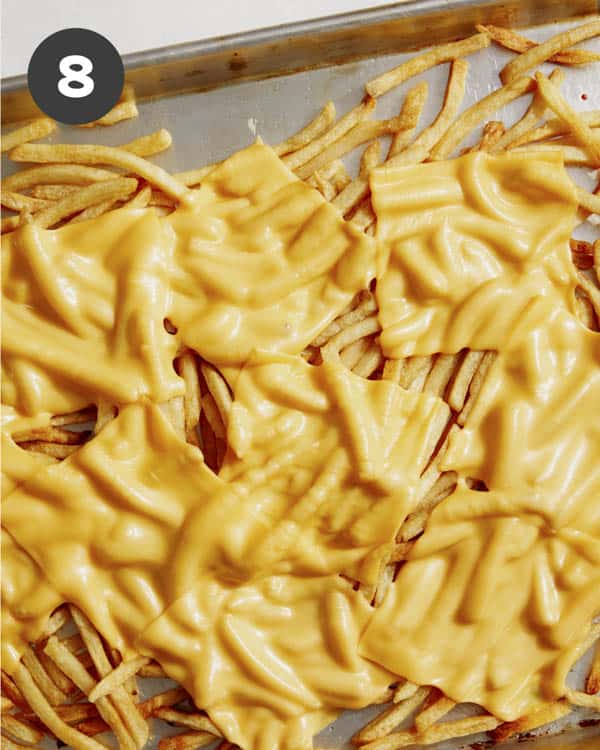 Cheese melted on a baking sheet with fries. 