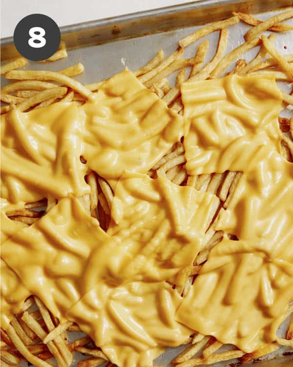 Cheese melted on a baking sheet with fries.