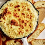 Baked garlic bread dip in a skillet with bread on the side.