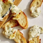 Baked garlic bread dip on crostini for an appetizer.