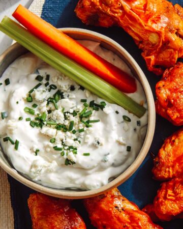 Blue cheese dressing in a bowl with carrots and celery.