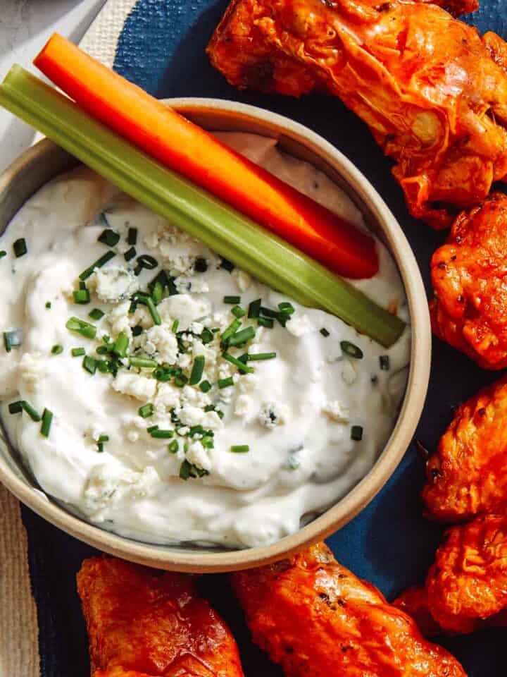 Blue cheese dressing in a bowl with carrots and celery.