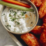 Homemade blue cheese dressing in a bowl served with buffalo wings.