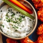 Blue cheese dressing in a bowl with carrots and celery.