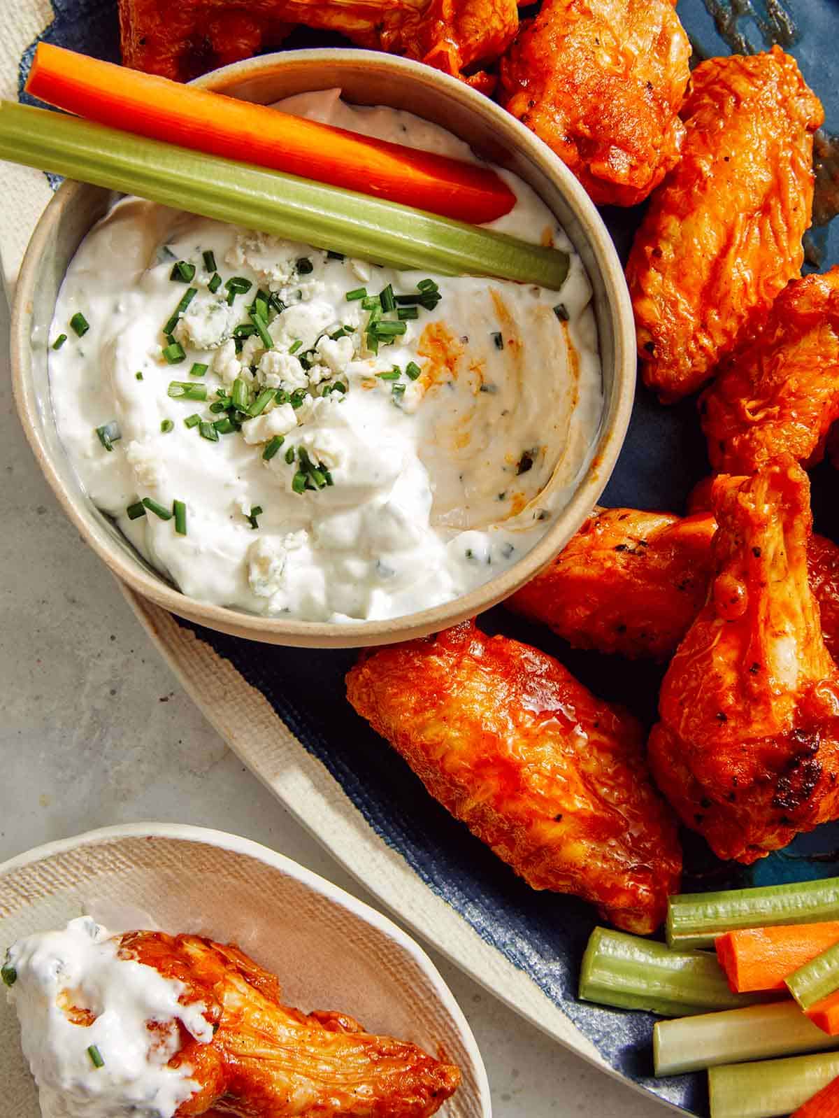 Blue cheese dressing served with buffalo wings on a platter. 