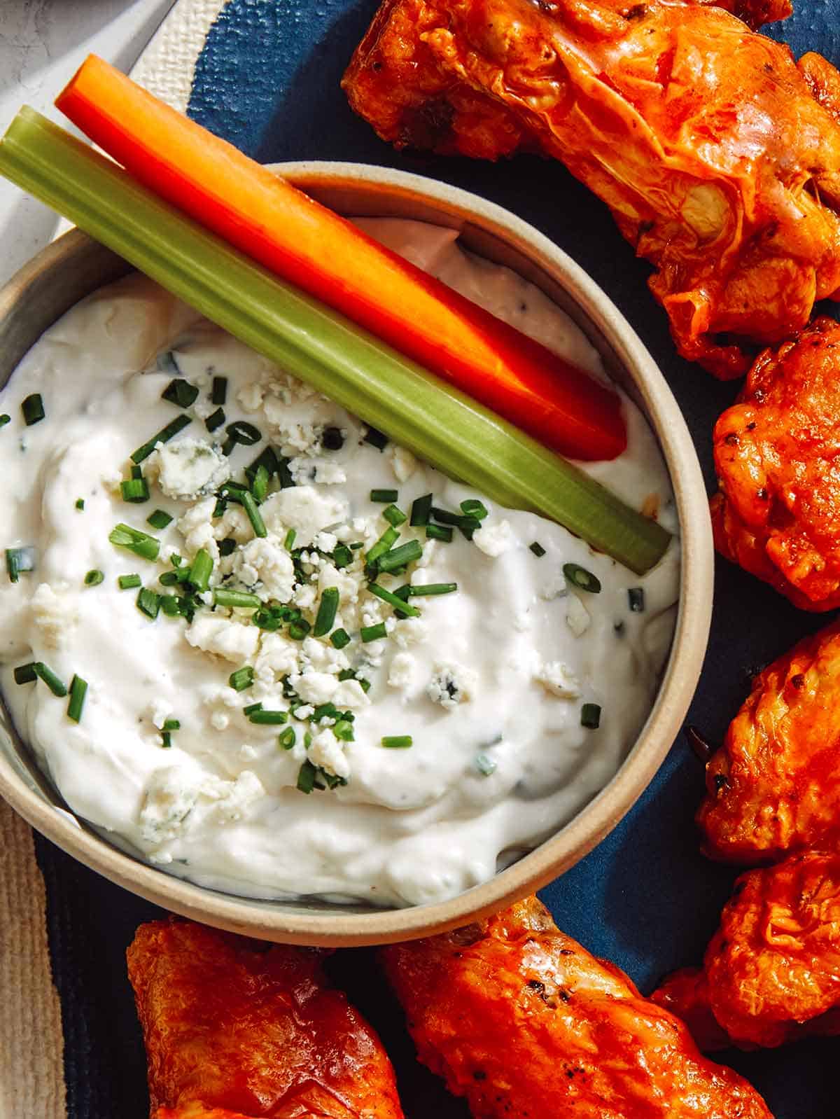 Blue cheese dressing in a bowl with carrots and celery. 