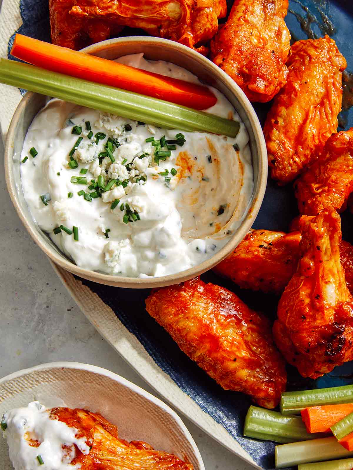 Air fryer buffalo wings being dipped in blue cheese dressing.