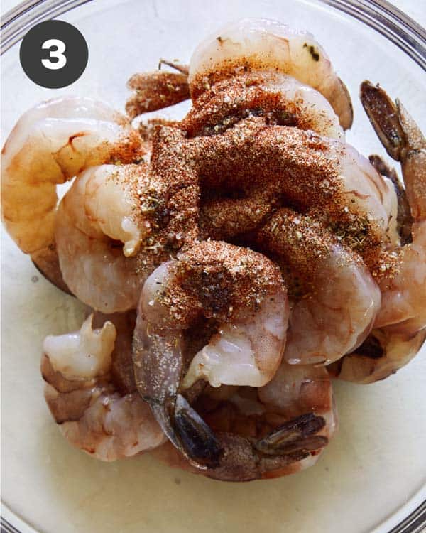 Shrimp with seasonings on top in a glass bowl.