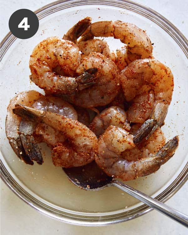 Shrimp in a bowl mixed with seasoning.