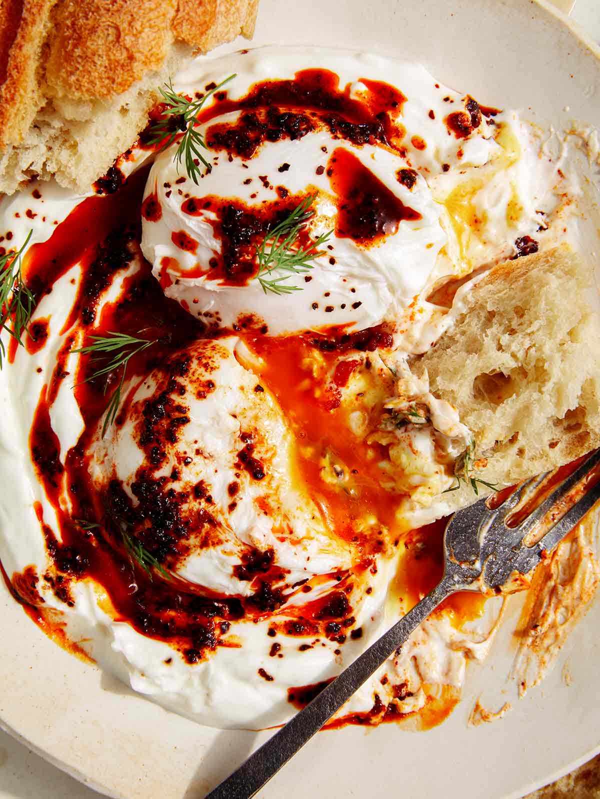 Cilbir eggs with bread on a plate. 