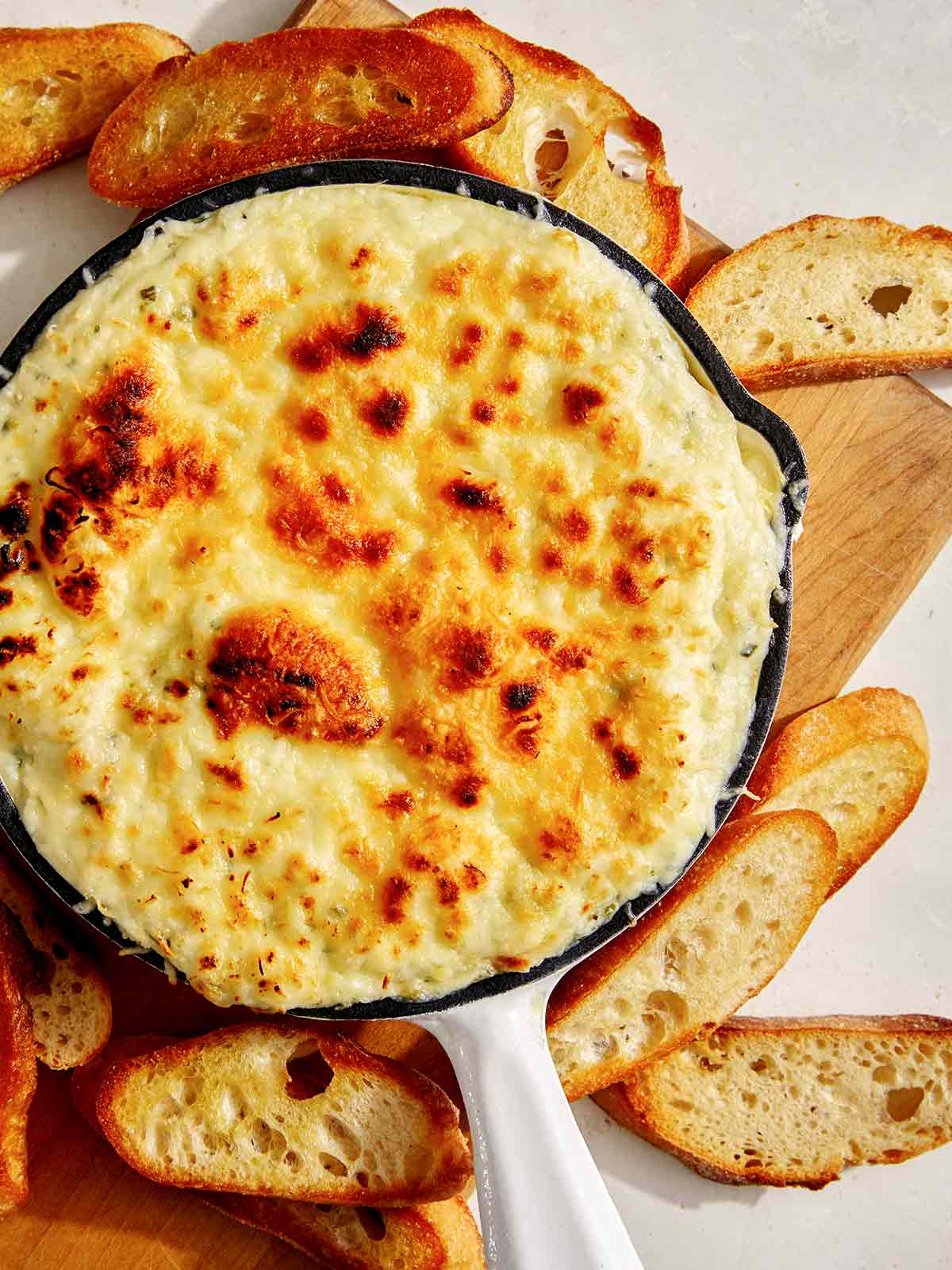 Baked garlic bread dip in a skillet with bread on the side. 