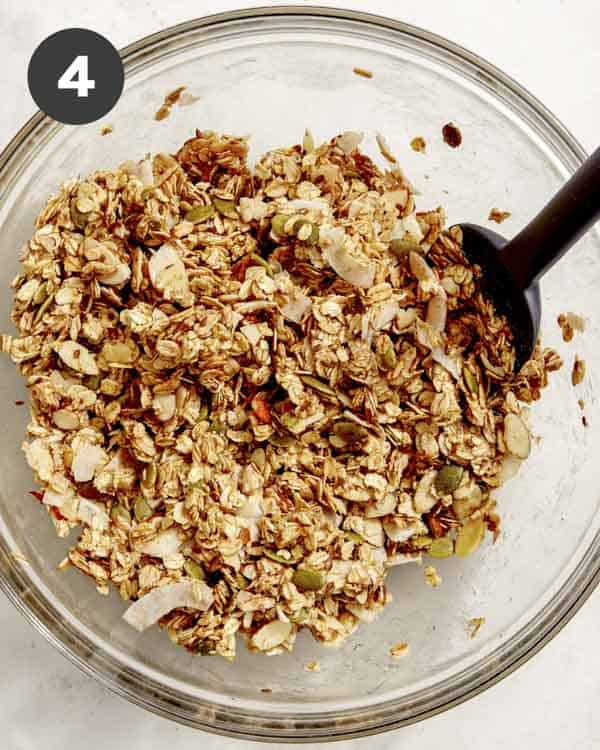 Dry ingredients of granola mixed together with honey in a bowl. 