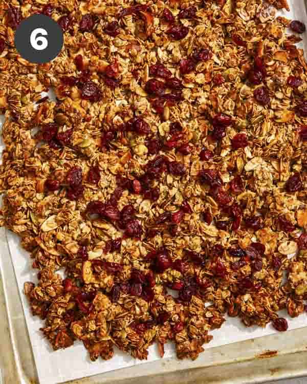 Homemade granola on a baking sheet right our of the oven topped with dried fruit. 