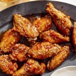 Air fryer chicken wings on a platter with beer next to it.