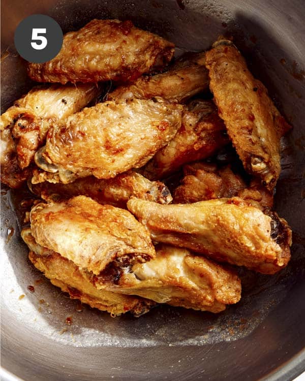 Chicken wings in a bowl about to be tossed with sauce. 